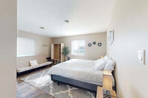 A bedroom with a bed, a sofa, a wardrobe, and a window. - Sunny - 3rd floor, spacious condo with kitchen, balcony & canal views (Ocean City)