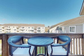 A wooden deck with a round table and two wicker chairs, overlooking a residential area with apartment buildings. - Sunny - 3rd floor, spacious condo with kitchen, balcony & canal views (Ocean City)