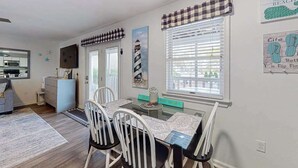 A dining area with a table, chairs, and a window with blinds. - Marathon North 103 (Ocean City)