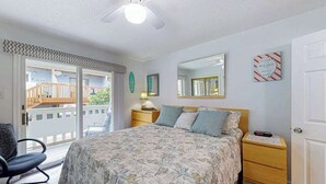 A bedroom with a bed, a chair, a nightstand, a mirror, and a door. - Marathon North 103 (Ocean City)