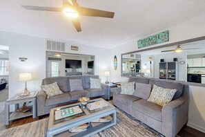 A living room with two grey sofas, a coffee table, and a ceiling fan.