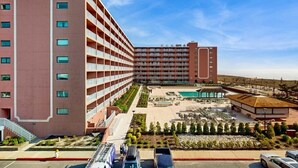 Ein mehrstöckiges Hotel mit Poolbereich, Außengastronomie und einem angelegten Garten.