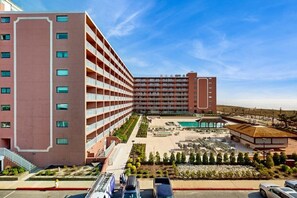 Ein mehrstöckiges Hotel mit Poolbereich, Au ßengastronomie und einem angelegten Garten.