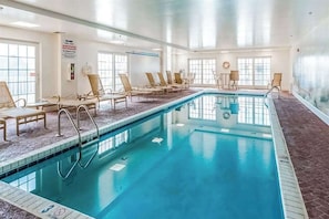 Ein Schwimmbecken mit Liegestühlen, einem Warnschild und großen Fenstern.