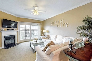 Ein Wohnzimmer mit Kamin, Fernseher, Deckenventilator und einem Wandschild mit der Aufschrift 'OCEAN CITY'.
