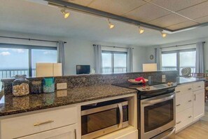 Eine Küche mit Granit Arbeitsplatten, Edelstahlgeräten und großen Fenstern mit Ausblick.