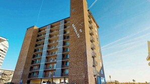 Un immeuble à plusieurs étages, doté d’une façade en briques, de balcons et surplombant un ciel dégagé.