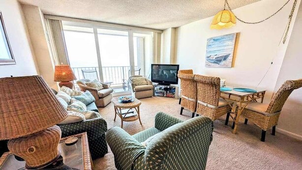 Un salon avec des meubles en osier, un téléviseur et un balcon.