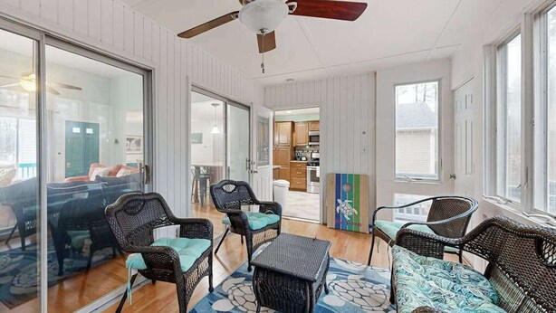 A room with wicker furniture, a ceiling fan, and a view to the outside. - Teal Haven (Ocean Pines)