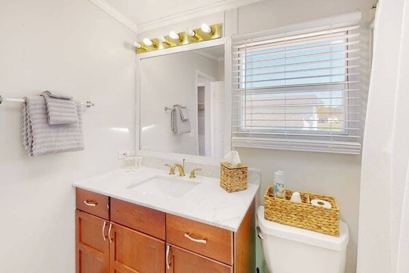 A bathroom with a vanity, two sinks, a mirror with lights, a towel rack, and a window with blinds. - Assateague Pointe - Yardarm (Berlin)