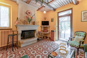 A cozy living room with a fireplace, a television, a patterned floor, and a green armchair.