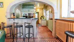 Una cucina con un arco, sgabelli da bar, un frigorifero e una finestra con tende.