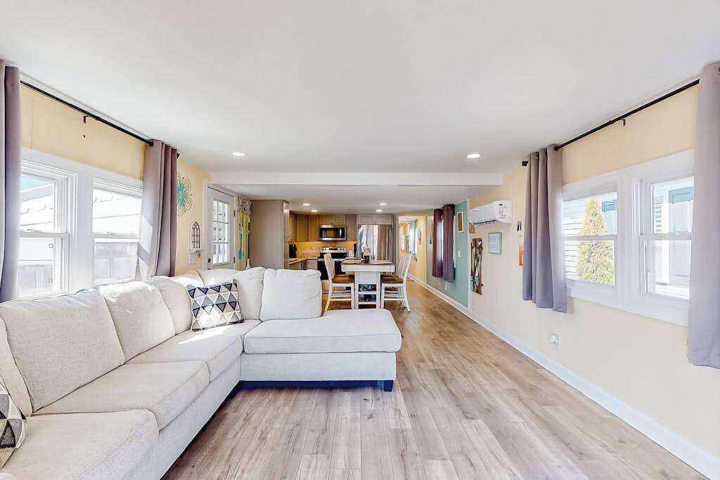 A modern living room with a sectional sofa, a dining area, and a kitchen in the background.