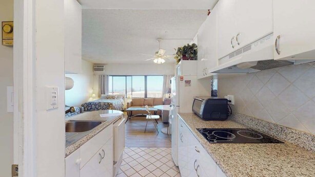 A compact kitchen with a stove, sink, and cabinets. - Comfortable ocean-view studio with pool (Ocean City)