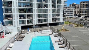 Ein mehrstöckiges Hotel mit Balkonen, einem Schwimmbad und einem Parkplatz.