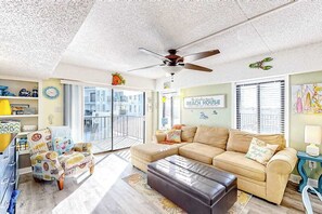 Ein Wohnzimmer mit einer Couch, einem Hocker und einem Sessel mit bunten Mustern.