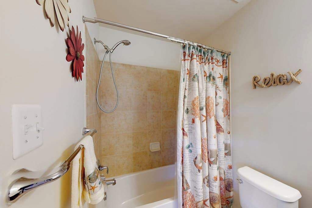 A bathroom with a shower, toilet, and towel rack.