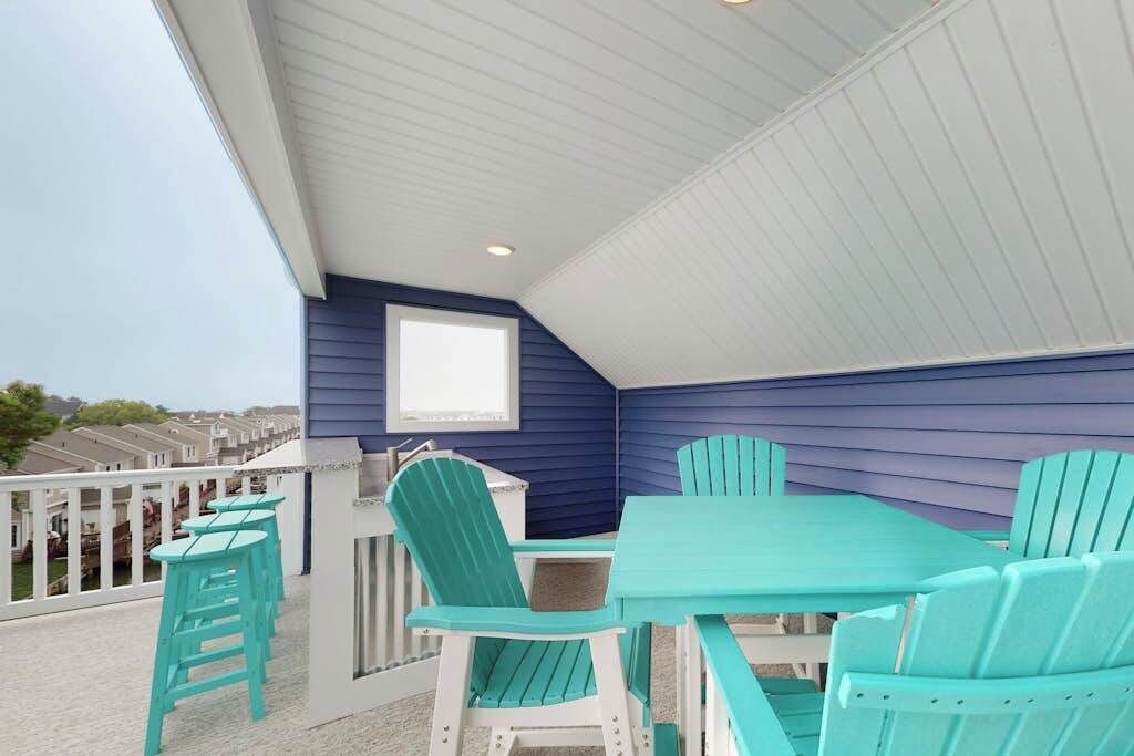 A covered outdoor area with a table and chairs, a window, and a view of other buildings.