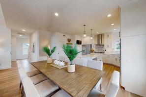 A modern kitchen with white cabinets, a wooden dining table, and recessed lighting. - Sapphire Sol | House in Ocean City with elevator, roof deck, grill, streaming (Ocean City)
