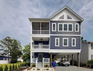 A two-story residential building with a balcony on the upper floor and a garage at the front. - Sapphire Sol | House in Ocean City with elevator, roof deck, grill, streaming (Ocean City)