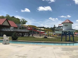 A water park with a pool, water slides, and a lighthouse-like structure. - Assateague Pointe - Helmsman (Berlin)