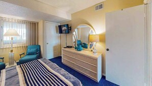 Une chambre d’hôtel avec un lit, une commode, une télévision et une fenêtre avec des rideaux.