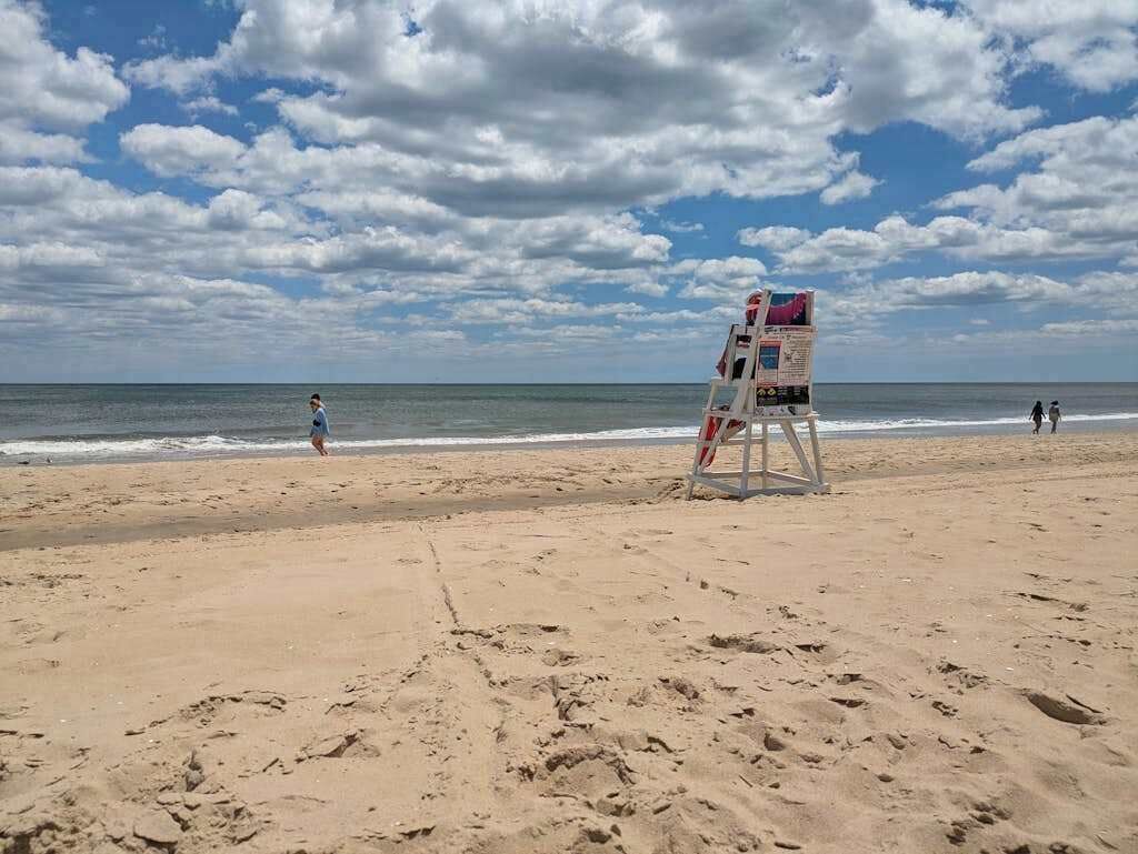 A beach with a lifeguard tower, sandy beach, and ocean.