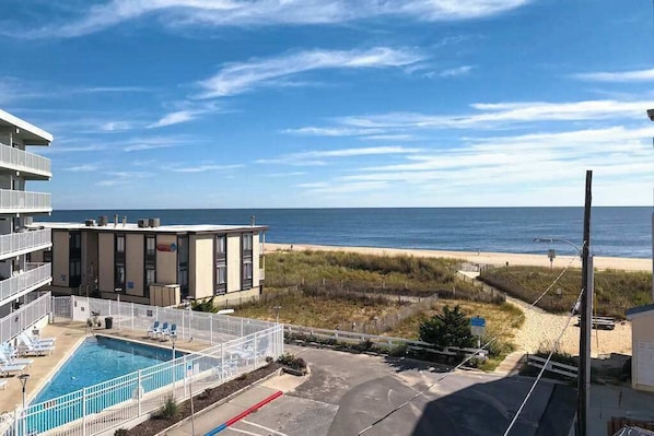 Un hotel con piscina, vistas a la playa y zona de estacionamiento.