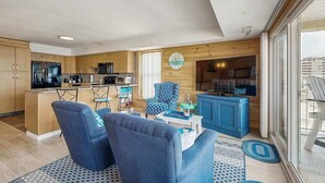 Een moderne keuken met een centraal eiland, een eethoek met blauwe stoelen en een woonkamer met een blauwe bank.