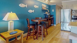A dining area with a table and chairs, a lamp, and a wall with fish decorations. - Breakaway East 107 (Ocean City)