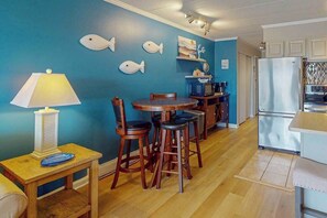 A dining area with a table and chairs, a lamp, and a wall with fish decorations. - Breakaway East 107 (Ocean City)