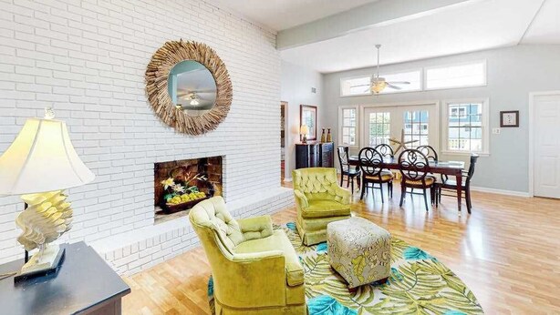 A spacious living room with a fireplace, a dining area, and a large window providing natural light. - Bayside Keys 627 (Ocean City)