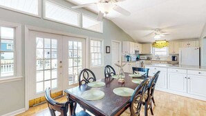 A spacious kitchen with a dining table, chairs, ceiling fans, and a view of the outside. - Bayside Keys 627 (Ocean City)