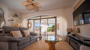A modern living room with a grey sofa, a glass coffee table, and a TV mounted on the wall. - CostaBlancaDreams - Casa Kaiyo in Calpe (Calpe / Calp)
