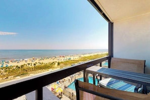 A balcony with a view of a beach and a pool. - Oceanfront condo with a balcony, central AC, pools, game room & sports courts (Ocean City)