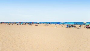 Een strand met mensen, parasols en strandstoelen.