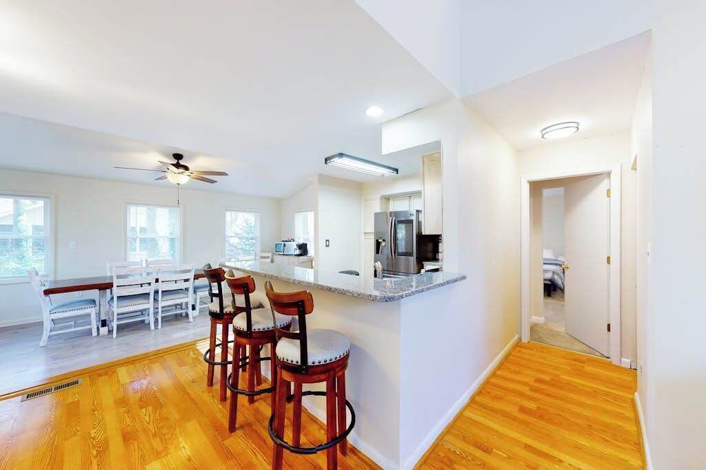 A modern kitchen with a bar area, wooden flooring, and a dining set.