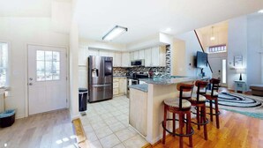 Una cocina moderna con una isla central, electrodomésticos de acero inoxidable y una zona de bar con taburetes.