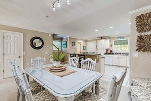 A dining area with a glass-top table, white chairs, a potted plant, and a mirror on the wall. - End-unit townhome with resort amenities, water view, balcony, fireplace, & AC (West Ocean City)