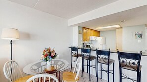 Un comedor con una mesa redonda, sillas, una lámpara y un jarrón con flores.