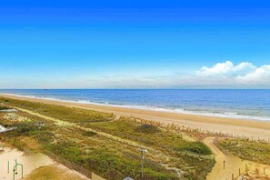 Ein Strand mit freiem Blick auf den Ozean, einem sandigen Pfad und etwas Vegetation.