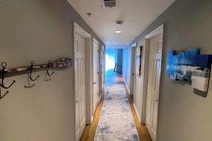 A hallway with doors, a patterned carpet, and wall-mounted artwork. - The View 402 (Ocean City)