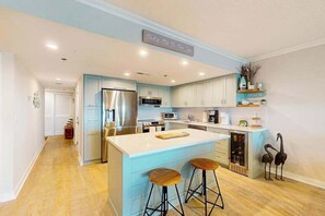 Une cuisine moderne avec des meubles de couleur bleu clair, des appareils en acier inoxydable et un îlot central doté de tabourets.