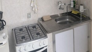 Een keuken met witte kastjes, een roestvrijstalen spoelbak, een fornuis en een magnetron.