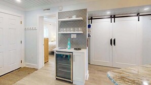 Une cuisine moderne avec des meubles blancs, un four encastré et un petit réfrigérateur.