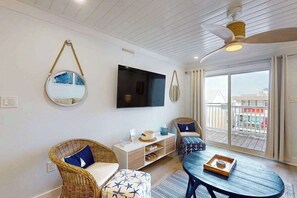 A living room with wicker furniture, a flat-screen TV, a ceiling fan, and a balcony with a view. - Tiffanie By The Sea 323D (Ocean City)
