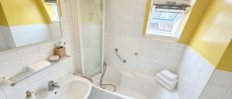 Un baño con lavamanos blanco, bañera, ducha y ventana.