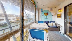 Ett rum med utsikt över en vattenyta, ett vitt bord, blå stolar, en soffa och en vägg med en välkomstskylt.