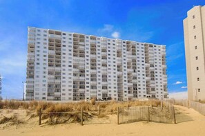 A multi-story hotel with a uniform facade, balconies, and a sandy beach in the foreground. - Plaza 811 (Ocean City)