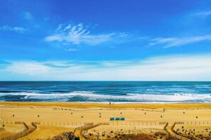 A beach with a clear sky, sandy shore, and a fenced area with structures. - Plaza 811 (Ocean City)